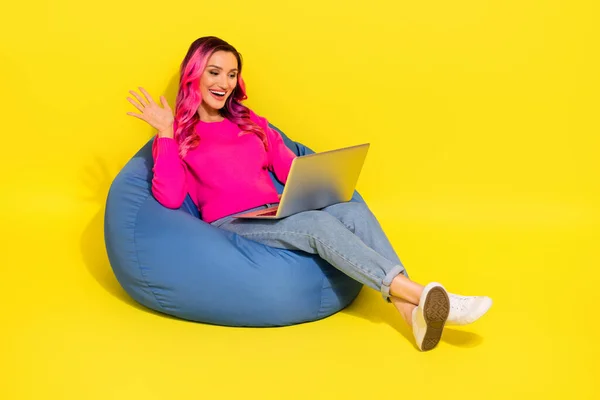 Full body portrait of excited funny lady sit comfy bag use netbook video call arm waving isolated on yellow color background.