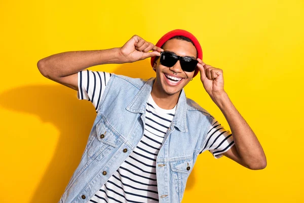 Photo of overjoyed satisfied person toothy smile hands touch sunglass isolated on yellow color background.