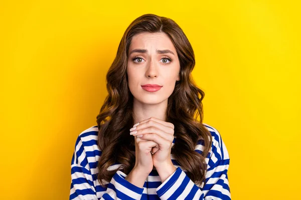 Photo of young nervous stressed depressed woman wear striped blue pullover hands together ask for help isolated on yellow color background.