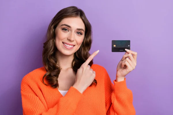 Photo of adorable stunning rich lady wear trendy orange clothes presenting new bank card for shopping isolated on purple color background.