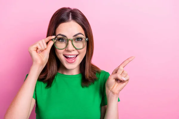 Photo of pretty cheerful girl arm touch glasses toothy smile direct finger empty space isolated on pink color background.