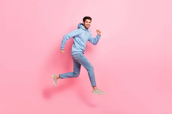 Full length profile side photo of cheerful man wear blue clothes running empty space store mall center isolated on pink color background.