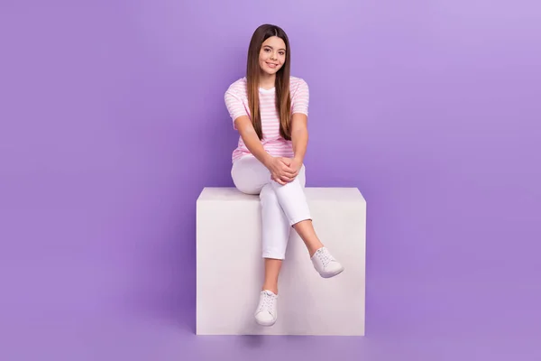 Full body portrait of adorable positive girl sit podium have good mood isolated on purple color background.