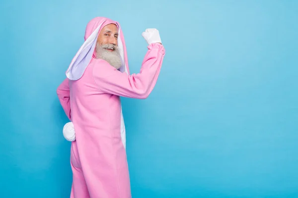 側プロフィール写真の正陽気な強い男の服を着たピンクウサギの衣装を示す腕の二足が青の色の背景に孤立 — ストック写真