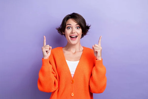 Photo of positive excited lady dressed orange cardigan showing up two fingers empty space isolated purple color background.