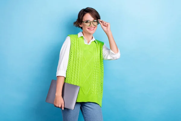Photo of young executive director company positive young girl wear green vest eyeglasses hold her netbook hp isolated on blue color background.
