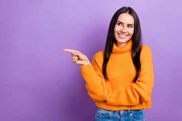 Photo of young smiling lady wear stylish clothes look interested indicate finger empty space promo shop brand isolated on purple color background.