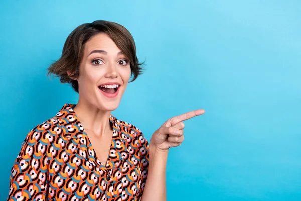 Photo of sweet excited lady dressed print shirt showing finger empty space isolated blue color background.