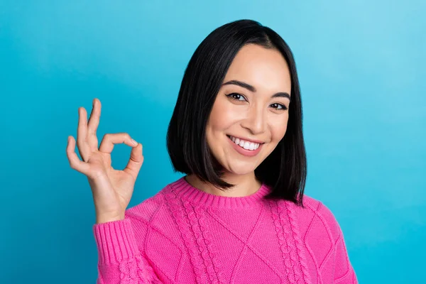 Photo of positive pretty malaysian girl beaming smile hand fingers demonstrate okey symbol isolated on blue color background.