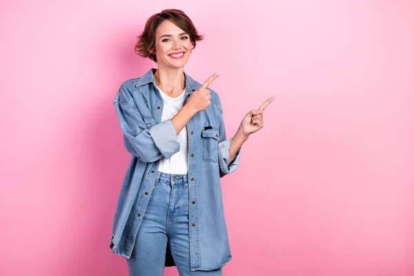 Photo of positive promoter lady wear denim jeans outfit indicating fingers mockup open clothes brand sale season isolated on pink color background.