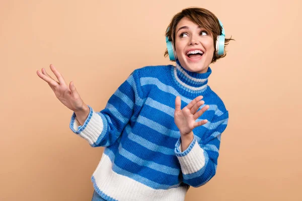 Photo of funky excited lady wear blue pullover headphones having fun looking empty space isolated beige color background.