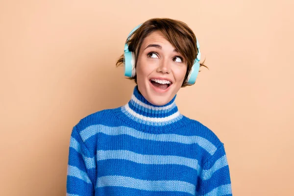 Photo of funny funky lady wear blue pullover headphones looking empty space isolated beige color background.