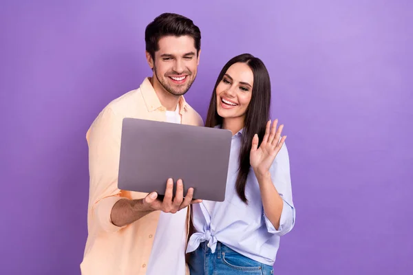 Photo of friendly people young friends wave palm hello online seminar remote hold new laptop internet connection isolated on violet color background.