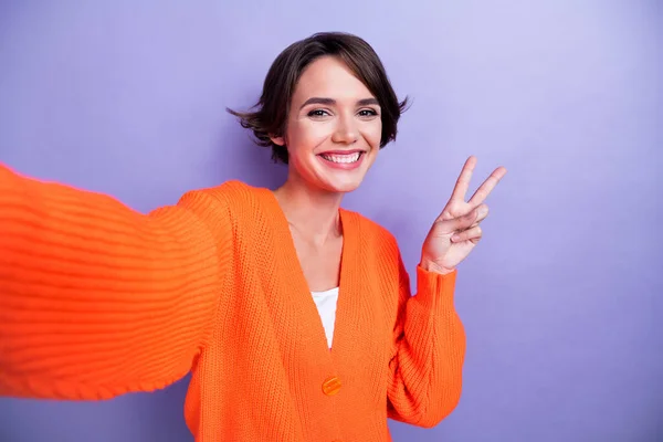 Photo of positive lovely lady wear trendy orange clothes demonstrate v-sign cool party empty space isolated on purple color background.
