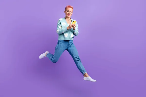アクティブなジャンプの女性のフル長さの写真屈託のない新しいサムスンのスマートフォン広告新しいアプリケーションのGoogleの再生は 紫の色の背景に隔離された — ストック写真