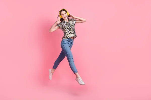 フルサイズの写真の屈託のないかわいい女の子ジャンプ手タッチヘッドフォン空のスペース隔離されたピンク色の背景 — ストック写真