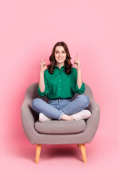 Full length photo of cute charming lady dressed green blouse sitting sofa showing two empty space isolated pink color background.