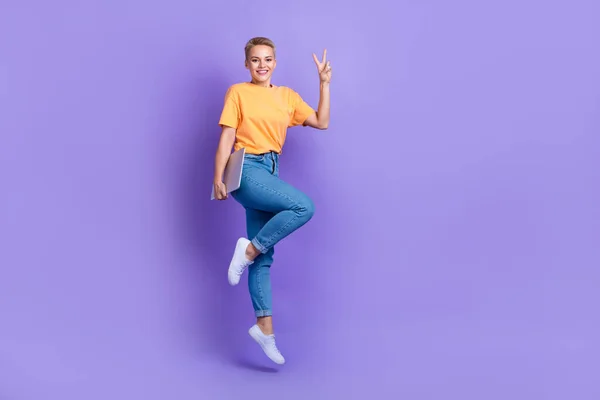 魅力的なエネルギーの女性ジャンプホールドネットブックショーV Sign孤立した紫の色の背景 — ストック写真