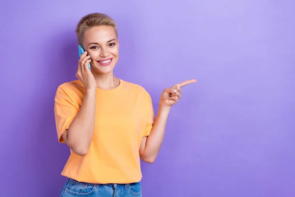 促销小姐身穿休闲橙色T恤衫电话的照片推荐使用紫色背景隔离的直接手指造型收费方案 — 图库照片