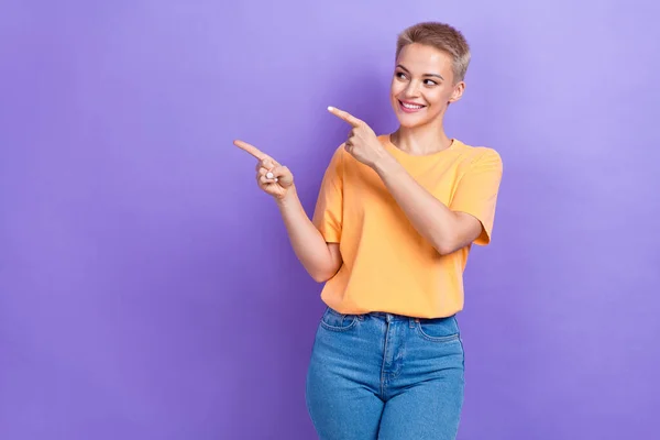 Photo of good mood smiling cheerful lady wear casual outfit looking indicate fingers empty space good news info isolated on violet color background.
