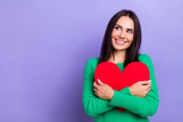 Photo of charming thoughtful woman wear green pullover hugging heart looking empty space isolated purple color background.