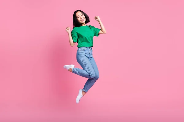 Full size photo of lovely woman wear oversize t-shirt jeans clenching fists looking forward to shopping isolated on pink color background.