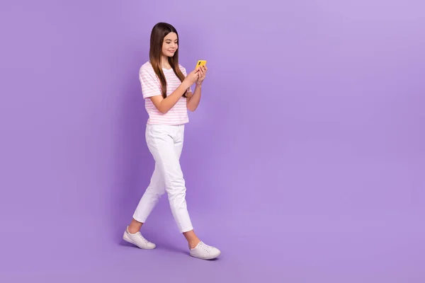 フルサイズプロフィールポートレートの魅力的な正の女の子歩く使用電話空のスペース孤立した上の紫の色の背景 — ストック写真