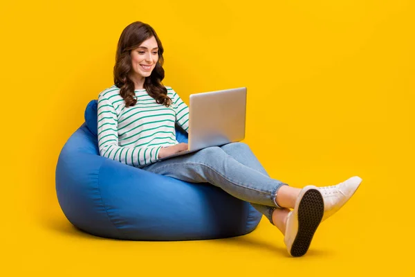 긍정적 여성의 의자에 노란색 배경에서 노트북 타이핑 이메일을 — 스톡 사진