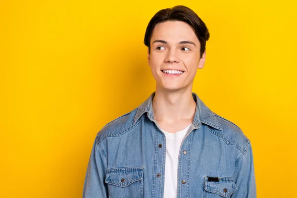 Photo of positive minded person beaming smile look empty space advert isolated on yellow color background.