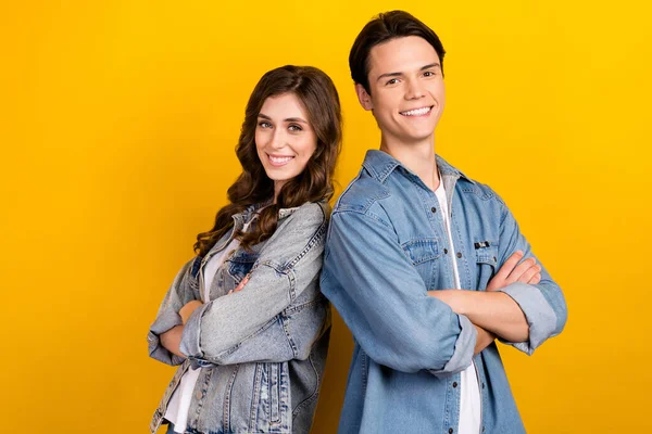 Photo of two cheerful nice people crossed hands beaming smile isolated on yellow color background.