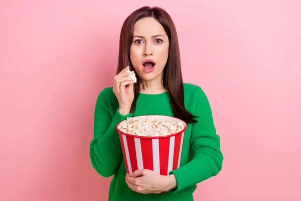 Photo of pretty impressed lady dressed green pullover eating pop corn watching interesting movie isolated pink color background.