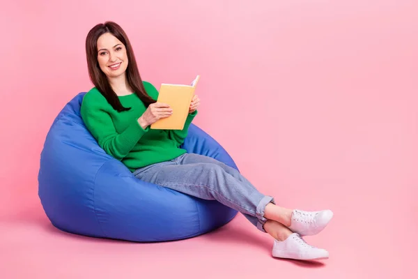 可愛い女性の写真緑のセーター座っている豆の袋読書ストーリー空の孤立したピンク色の背景 — ストック写真