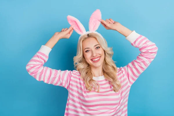 Photo of pretty sweet woman wear striped sweater holding bunny ears headband isolated blue color background.