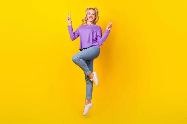 Vサイン手を示す美しい若い女性のジャンプ飛行の完全な長さの写真黄色の色の背景に隔離された流行の紫の服を着用 — ストック写真