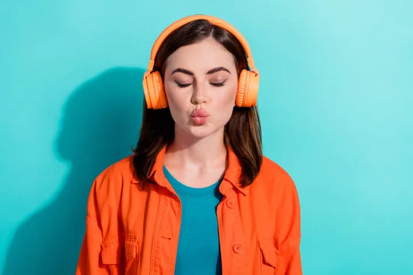 Photo of dreamy tender lady eyes closed wear orange stylish modern device listen romantic hits isolated on aquamarine color background.
