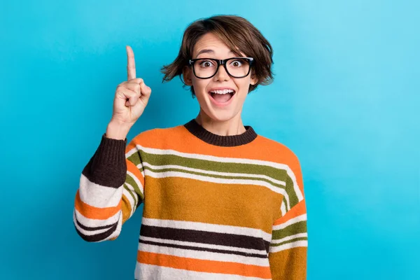 Photo of excited funky lady wear striped sweater spectacles pointing up empty space isolated blue color background.