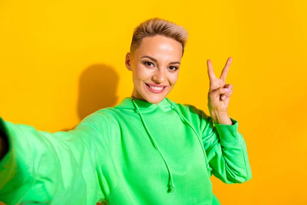 Portrait of gorgeous satisfied person toothy smile make selfie demonstrate v-sign isolated on yellow color background.