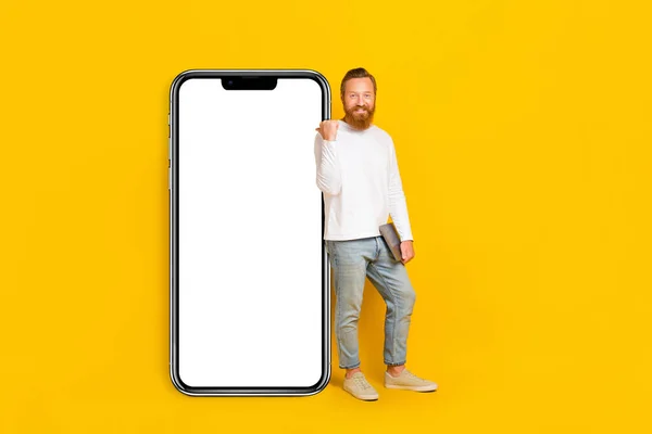 Full body photo of beard man hold laptop index promo wear shirt jeans shoes isolated on yellow color background.