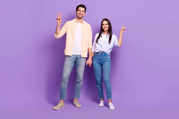 两个快乐伴侣的全身像 手挽手 展示紫色背景下的V形标志 — 图库照片