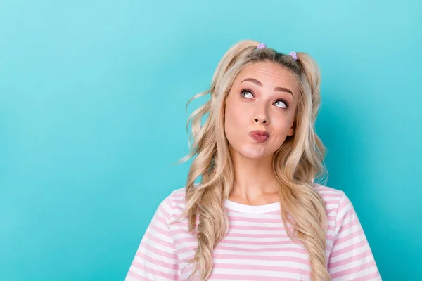 Photo of funny wavy blonde hair youth girl pouted lips wear pink striped t-shirt look deep think empty space isolated on aquamarine color background.