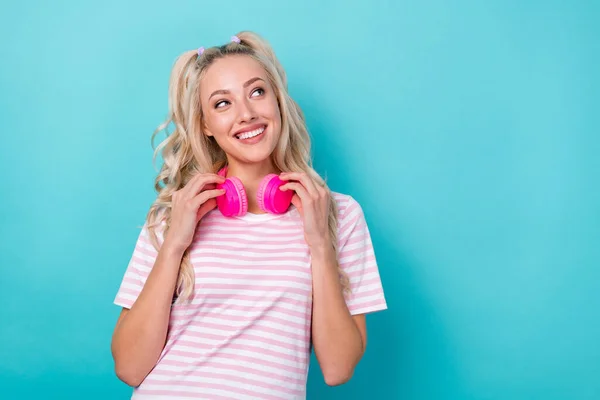 Portrait of pretty cheerful person toothy smile look empty space hands touch headphones hang neck isolated on blue color background.