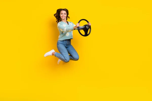 Full body profile portrait of crazy lady jumping arms hold wheel empty space isolated on yellow color background.