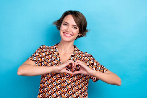 Photo of cute adorable woman wear print blouse showing arms heart chest empty space isolated blue color background.