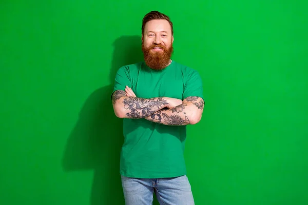 Photo of confident cheerful guy dressed t-shirt smiling arms crossed isolated green color background.