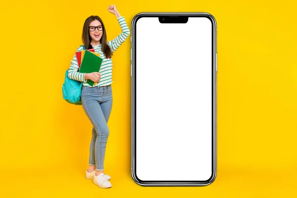 Full size image of charming overjoyed girl near placard promo raise fist in victory pass exam isolated on yellow color background.