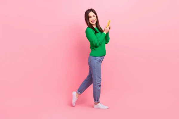 フルサイズプロフィール写真の陽気素敵な女の子ホールド使用スマートフォン空スペース広告隔離上ピンク色背景 — ストック写真