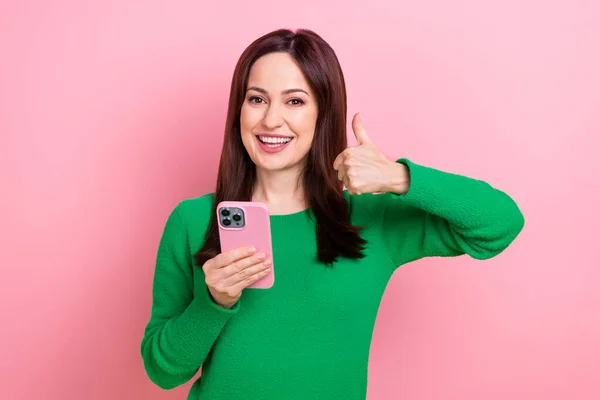 Photo of cool positive lady dressed green pullover showing thumb up texting modern gadget isolated pink color background.
