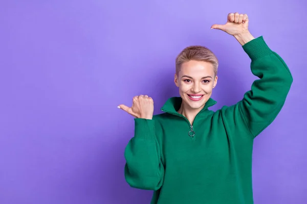 Portrait of cheerful pretty person toothy smile direct thumb fingers empty space isolated on purple color background.