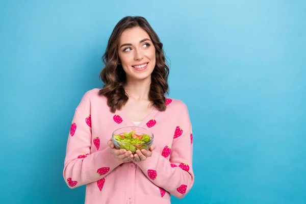 Photo of funky dreamy lady dressed pink cardigan holding salad bowl looking emtpy space isolated blue color background.
