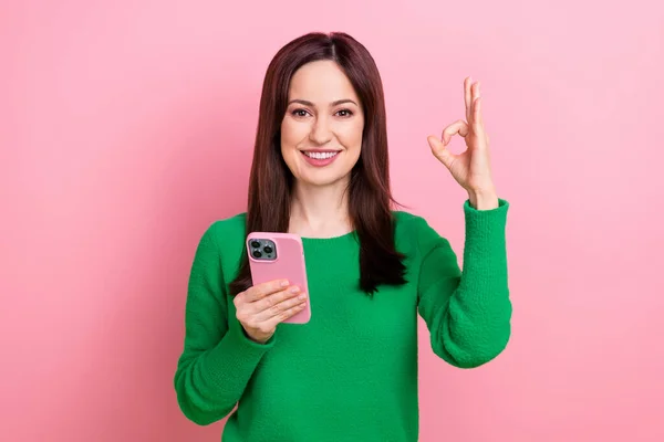 かわいいです自信のある女性の服緑のセーターショーキー読書アップルサムスンデバイス孤立ピンク色の背景 — ストック写真